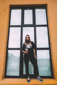 Portrait of woman standing against window