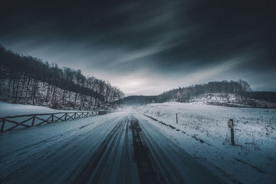 Snow covered road against sky at night
