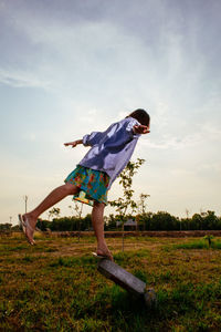 Rear view of woman standing on field against sky