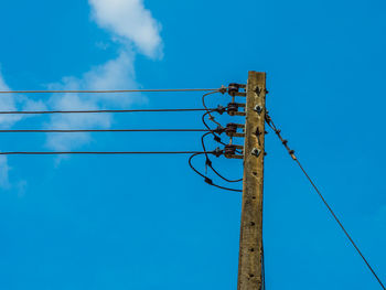 Low angle view of electricity pylon against blue sky