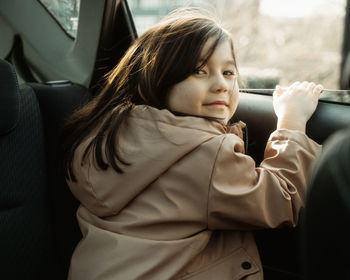 Portrait of young girl sitting in car and looking at camera