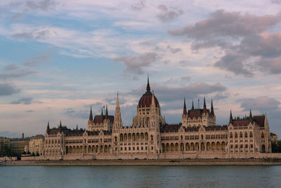 View of buildings at waterfront against cloudy sky