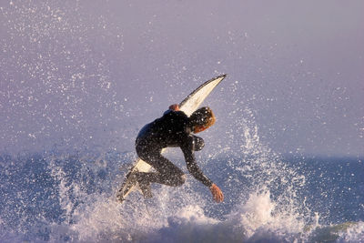 Man surfing in sea against sky