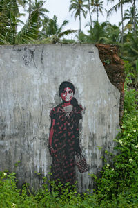 Portrait of young woman standing against trees