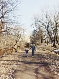 Full length of mother and daughter holding hands while walking on road