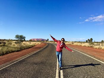 Full length of man walking on road against blue sky