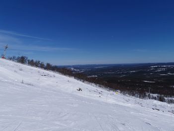 Snow covered land against blue sky