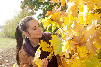 Woman looking at autumn tree in park