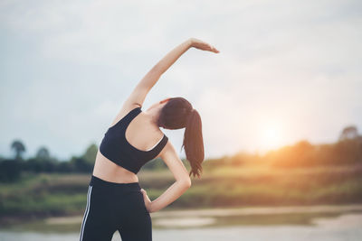 Girl exercising against sky