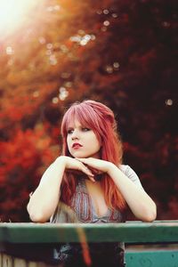 Thoughtful beautiful young woman with redhead looking away while standing by railing