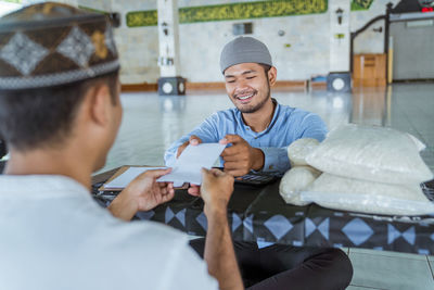 Smiling man receiving envelope in mosque