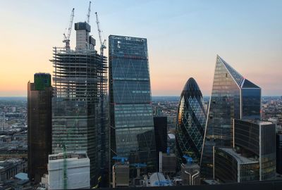 Modern buildings in city against sky during sunset