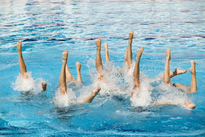 Low section of young women with feet up in swimming in pool