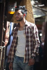 Young man looking away while standing in city