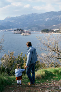 Rear view of father with son standing on mountain