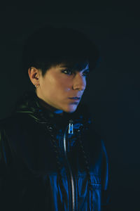 Portrait of young man against black background