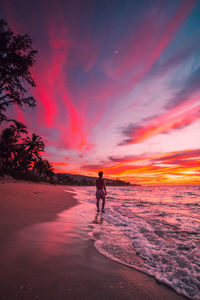 Silhouette woman walking at beach against sky during sunset