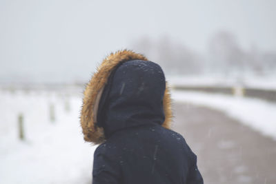 Rear view of woman standing on snow against sky