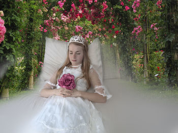 Rear view of woman with pink flowers against plants