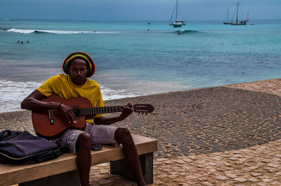 Man sitting on guitar at beach