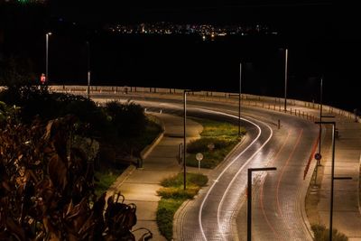 High angle view of road by illuminated city at night