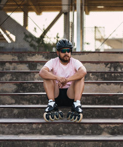 Full length of man wearing crash helmet sitting on steps