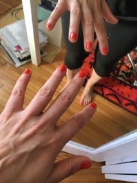 Cropped image of woman hand with red nail polish standing against mirror
