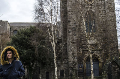 Young man in fur coat standing against church