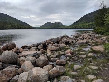 Rocks by river against sky