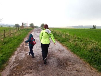 Mother and son walking on footpath against sky