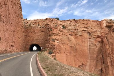 Road leading towards rock formation against sky