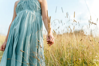 Midsection of woman standing on field against sky