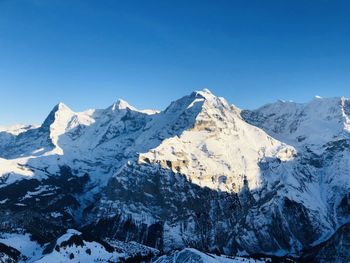 Scenic view of snowcapped mountains against clear blue sky