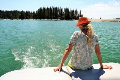 Woman sitting on boat in sea against sky