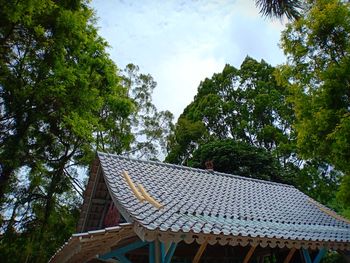 Low angle view of roof and trees against sky