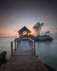 Pier over sea against sky during sunset