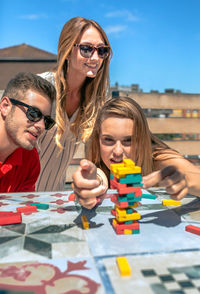 Concentrated woman looking game piece next to her friends in a rooftop party