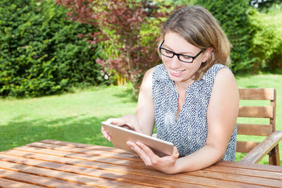 Young woman using phone while sitting on grass