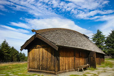 Wooden house on field against sky