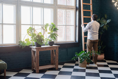 Male photographer working in stylish blue living room with plants