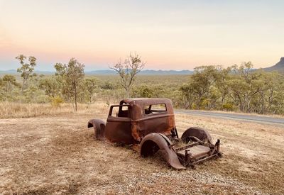 Abandoned car on field against sky