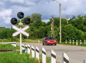 Car in front of a railway crossing. red traffic light at the railway crossing.