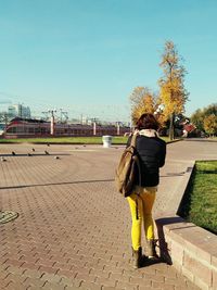 Rear view of woman walking on footpath against sky