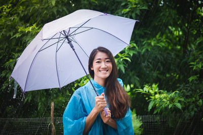 Portrait of smiling woman standing on wet rainy day