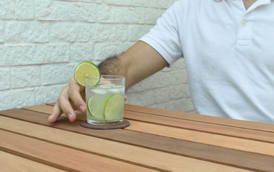 Midsection of man drinking glass on table