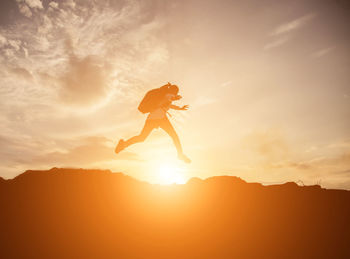 Silhouette woman jumping against sky during sunset