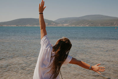 Rear view of woman at beach against sky