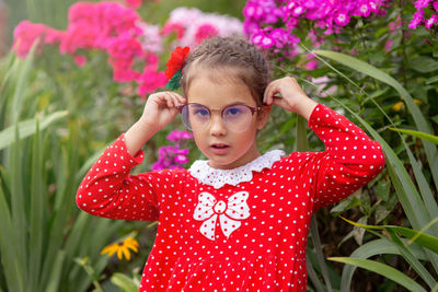 A portrait of a serious little girl straightens her glasses