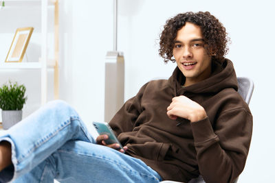 Portrait of young man holding phone sitting at office