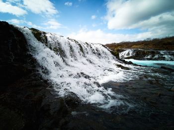 Scenic view of waterfall against sky